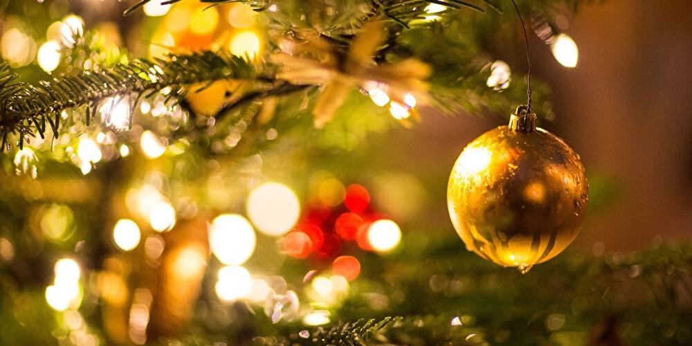 Eine goldene Kugel hängt an den Zweigen eines Weihnachtsbaums.
