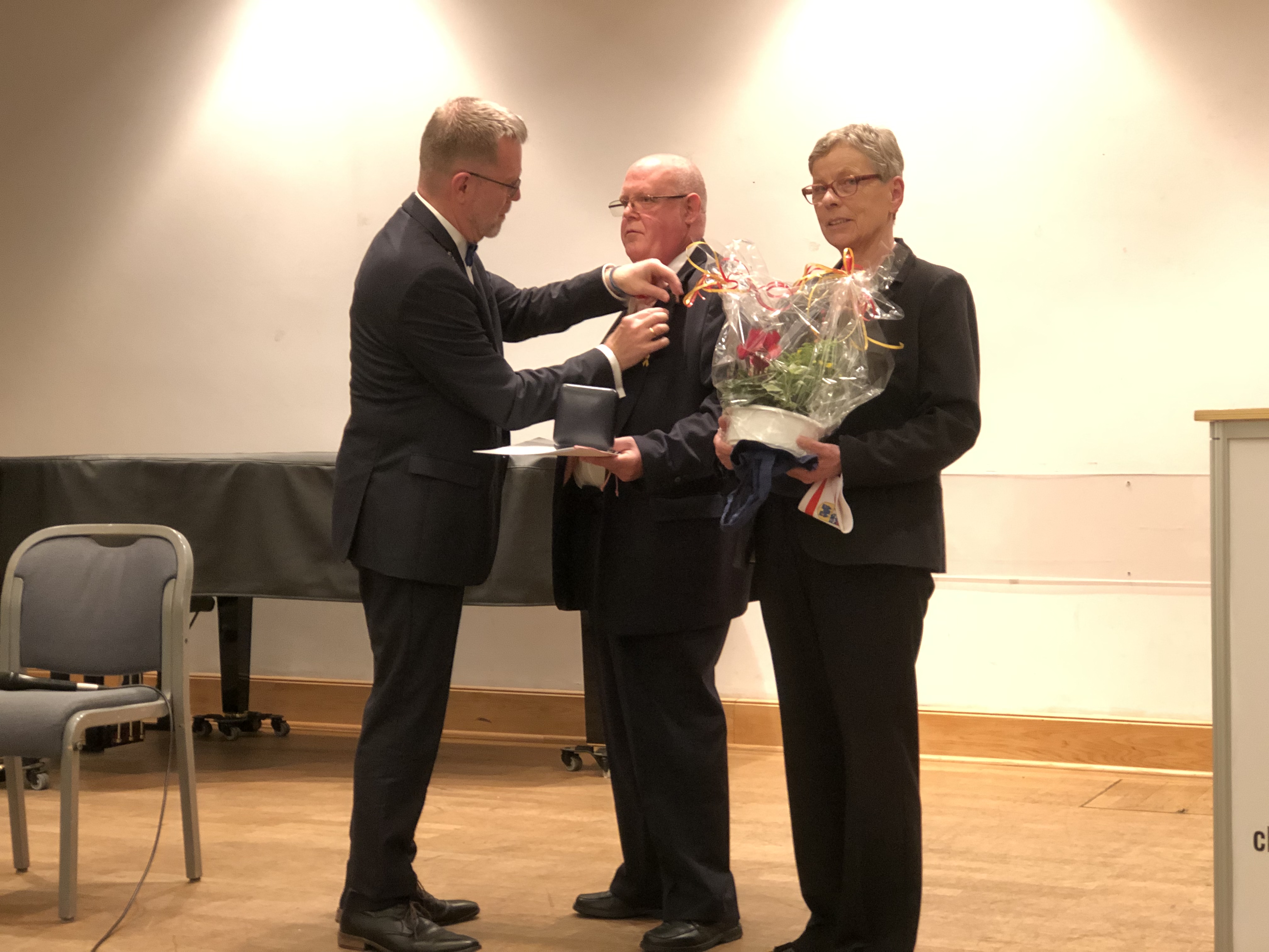 Bezirksbürgermeister Reinhard Naumann steckt Preisträger André Waaschke die Medaille an 