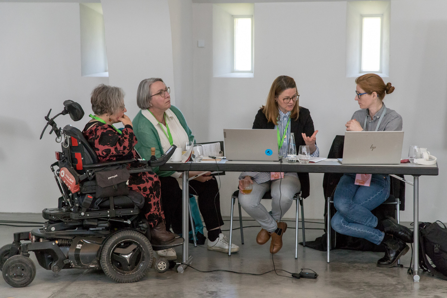 Vier der Organisatorinnen des Fachtags sitzen an einem Tisch mit zwei Laptops und unterhalten sich