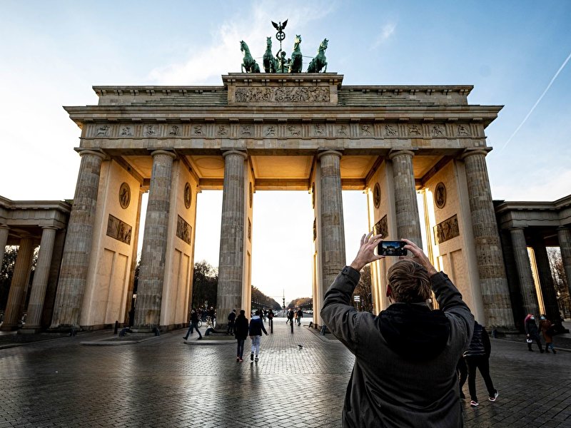 Ein Mann fotografiert bei sonnigen Wetter das Brandenburger Tor