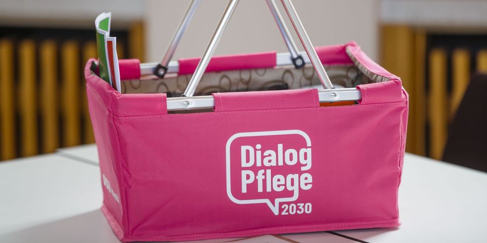 Pinkfarbener Korb mit Informationsmaterialien und der Aufschrift "Dialog Pflege 2030"