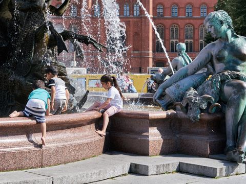 Kinder spielen am Neptunbrunnen