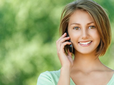 Lächende junge Frau mit Telefon am Ohr