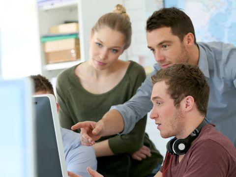 Gruppe junger Menschen arbeitet gemeinsam an einem Rechner