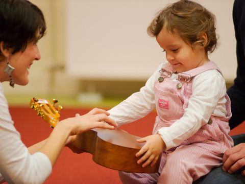 Ein Kind macht gemeinsam mit seinen Eltern erste Berührungen mit der Musik