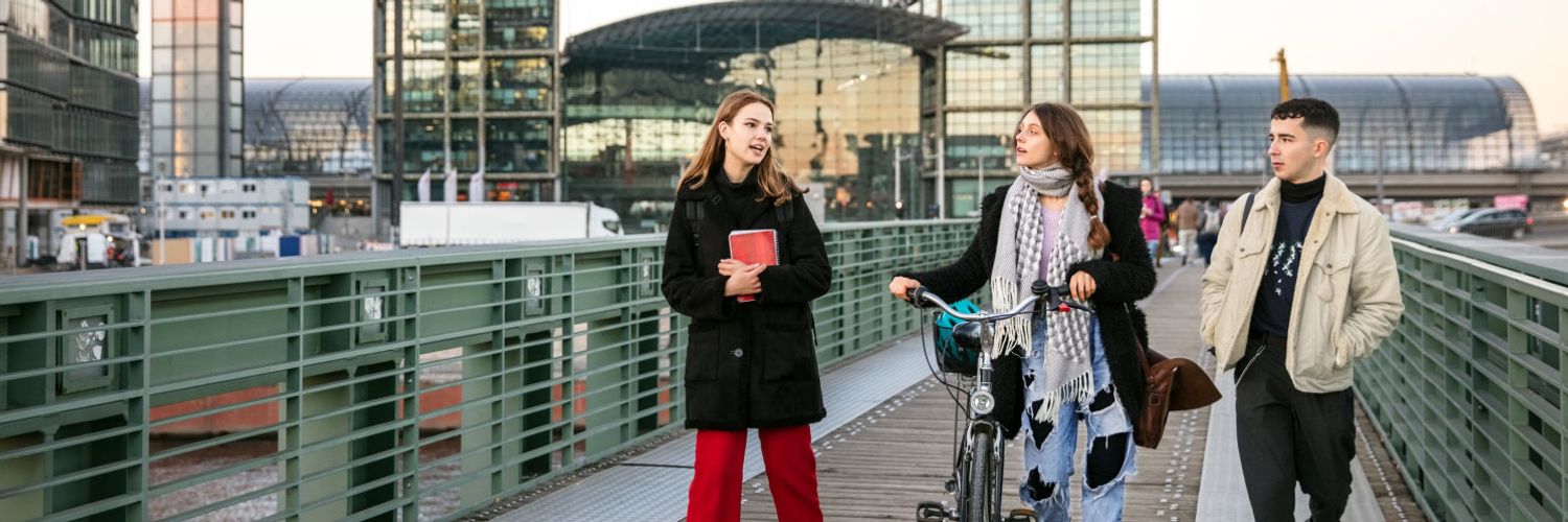 Gruppe von Studierenden laufen zusammen über eine Fußgängerbrücke über die Spree am Berliner Hauptbahnhof