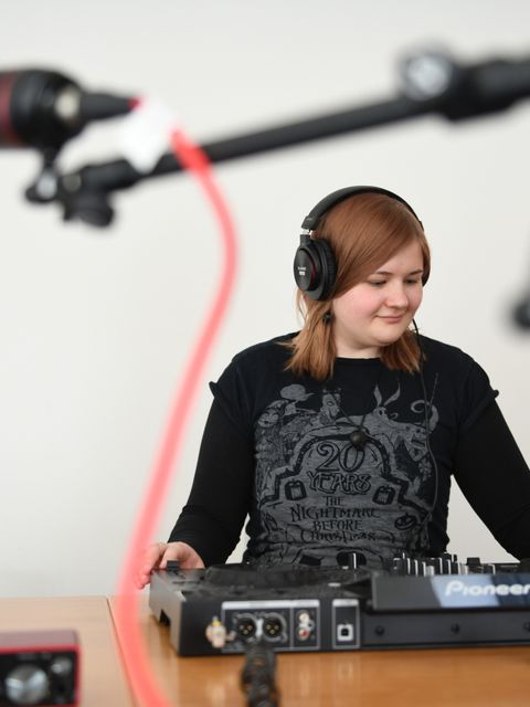 Junge Frau an DJ-Pult in MusikRaum