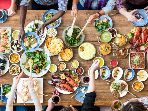 Multiethnische Leute essen am Tisch mit vielen Seisen verschiedener Länder