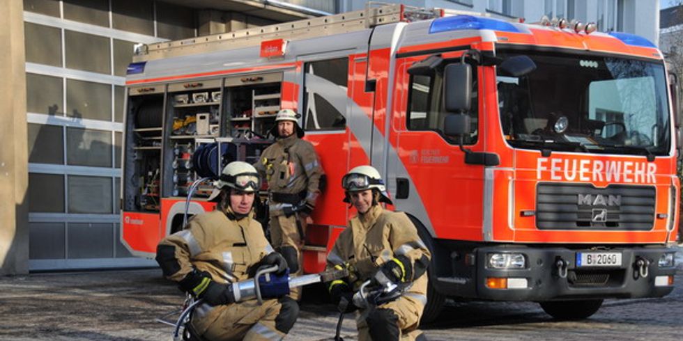 Drei Feuerwehrleute vor einem Einsatzfahrzeug