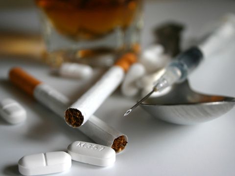 Zigaretten, Tabletten, Löffel und Spritze liegen auf einem Tisch