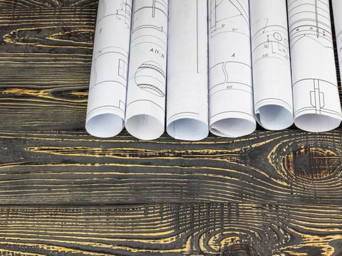 Papierrollen mit Projektzeichnungen auf Holzhintergrund