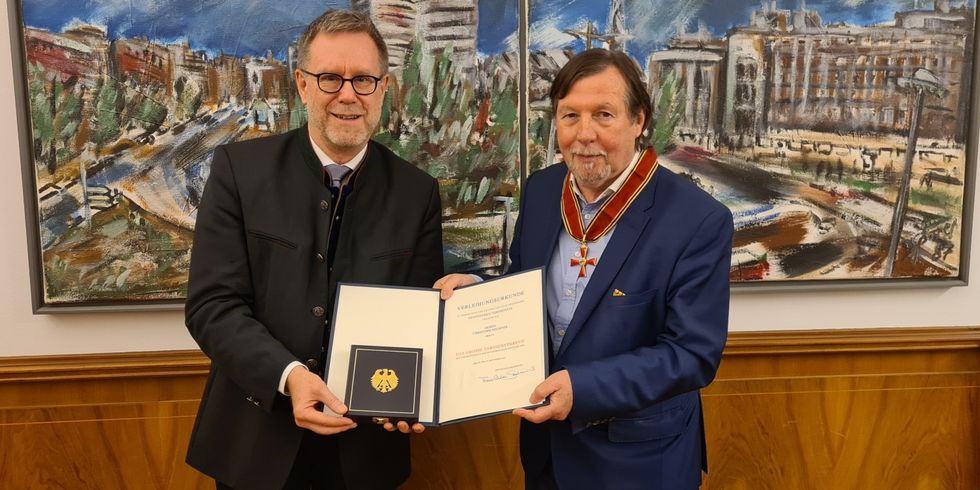 Bezirksbürgermeister Reinhard Naumann überreicht Christoph Heubner die Urkunde zum Großen Verdienstkreuz.