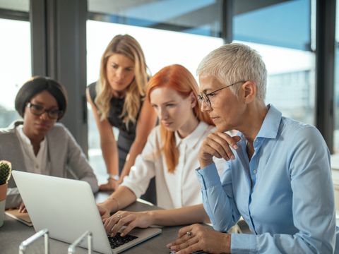 Gruppe von Unternehmerinnen arbeiten gemeinsam an einem Laptop