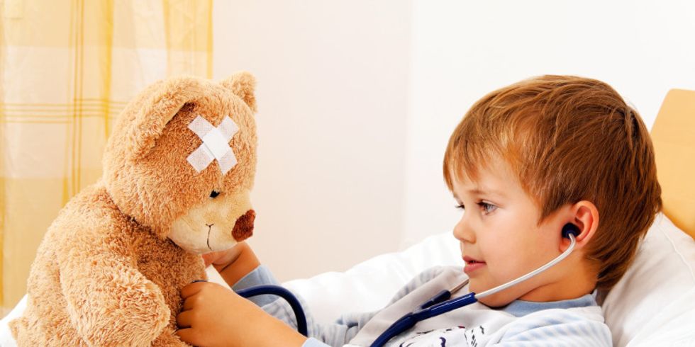 Krankes Kind untersucht Teddy mit Stethoskop