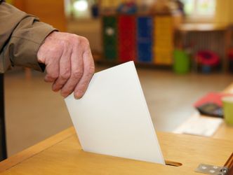 Stimmzettel wird in Wahlurne gesteckt