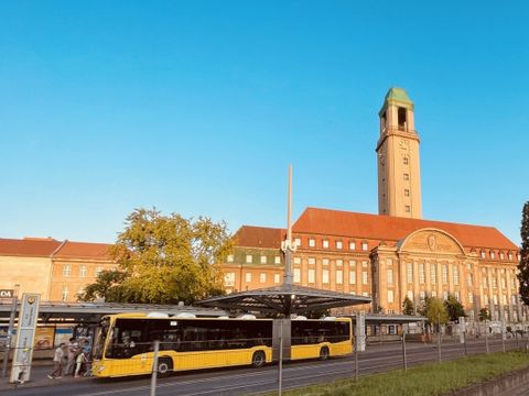 Ein gelber BVG-Bus hält direkt vor dem Rathaus Spandau