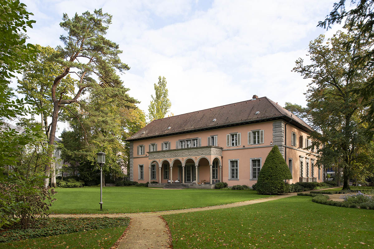 Gartenansicht des Landhaus Andreae mit Rasenfläche und Baubestand in Berlin-Grunewald