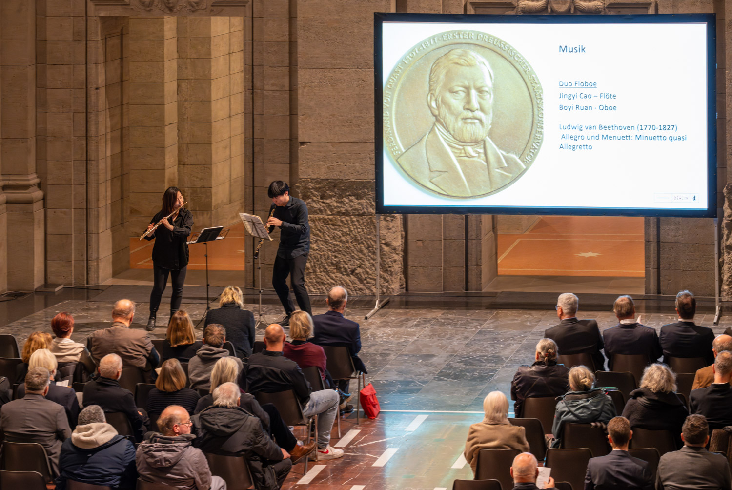 Verleihung Ferdinand-von-Quast-Medaille 2023: Blick über die Köpfe der Zuschauer zur Leinwand und dem spielenden Duo Floboe