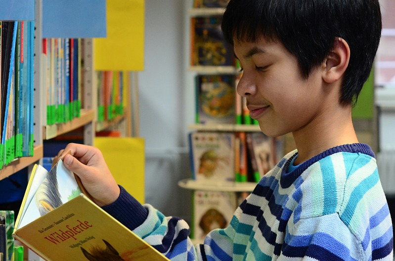 Junge in der Kinder- und Jugendbibliothek liest