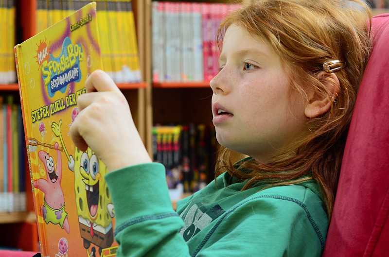 Mädchen liest Comic in der Bibliothek Heerstraße
