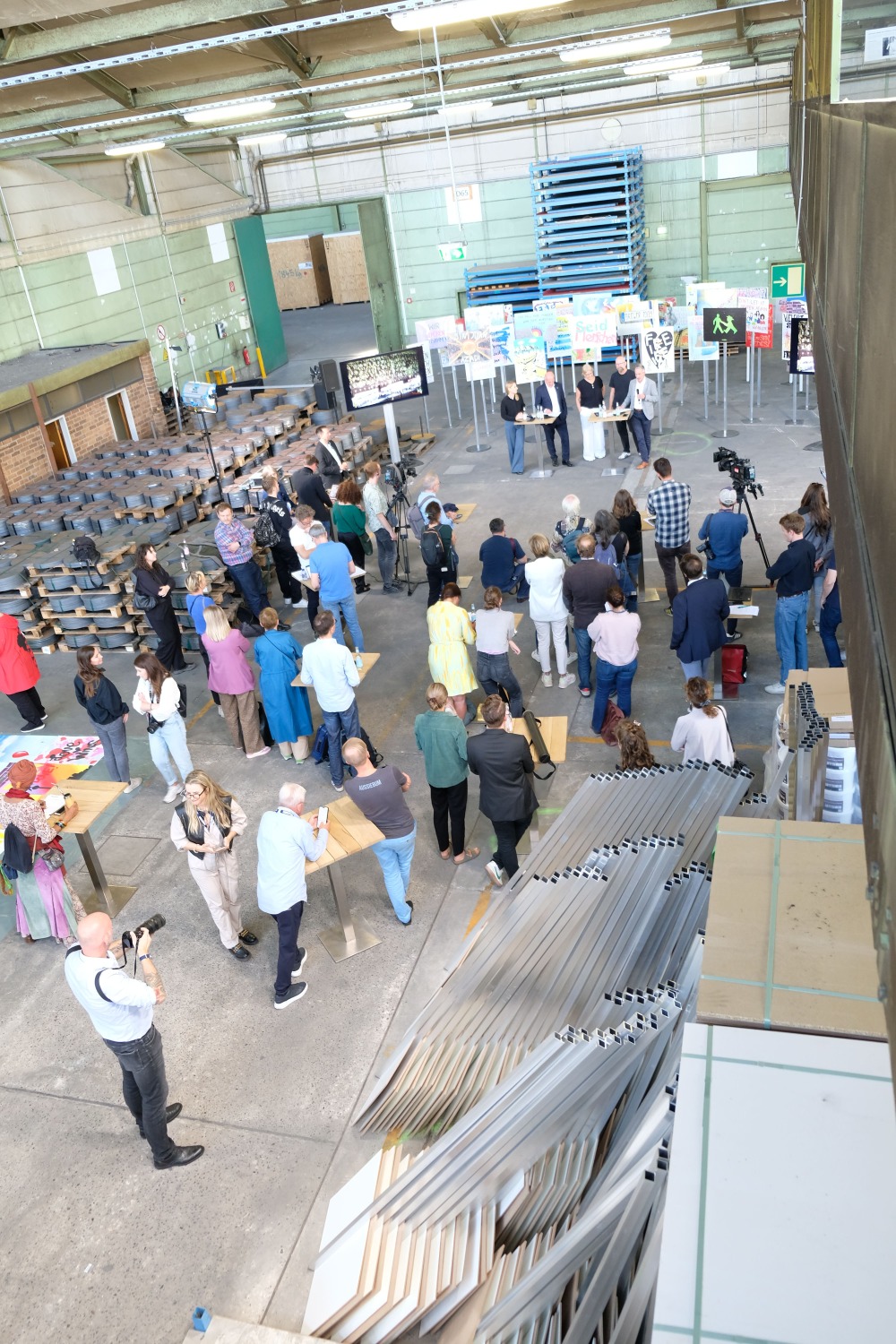 Die Pressekonferenz zum 35. Mauerfalljubiläum aus der Vogelperspektive. Zurzeit befinden sich die neu gestalteten Transparente noch in einer Neuköllner Lagerhalle, wo sie auf die Schilder (unten im Bild) aufgebracht werden.