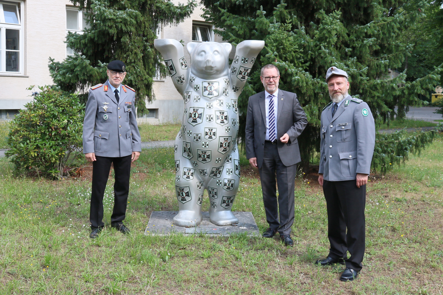 Bezirksbürgermeister und zwei Offiziere der Bundeswehr mit Buddybär