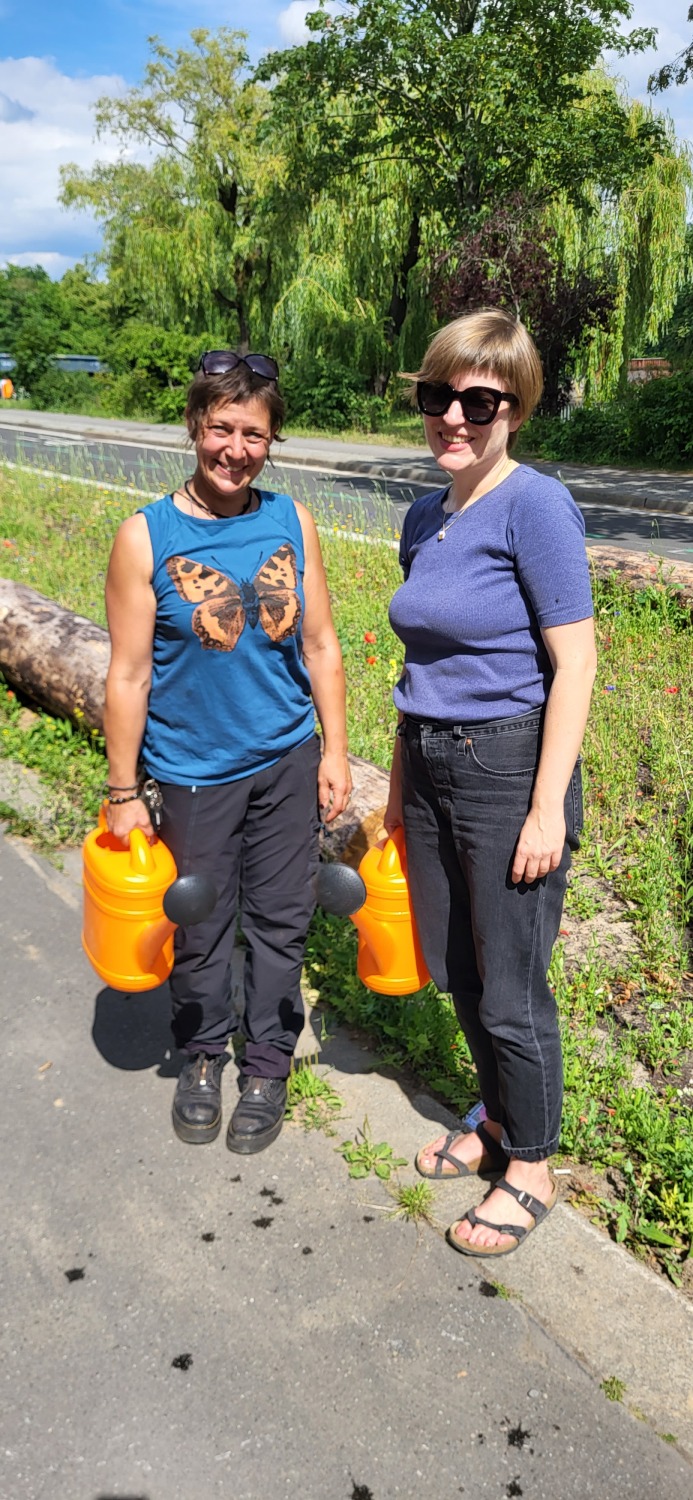 Umweltbildungskoordinatorin des Bezirksamts Katja Frenz und Bezirksstadträtin Annika Gerold versorgen die Neuanpflanzungen mit Wasser