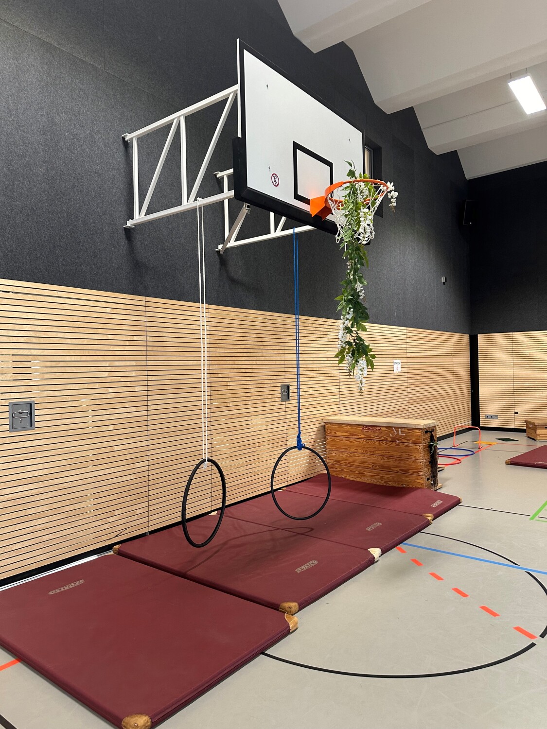 Ein aufgebauter Hindernisparkour mit Matten und einem Basketballkorb.