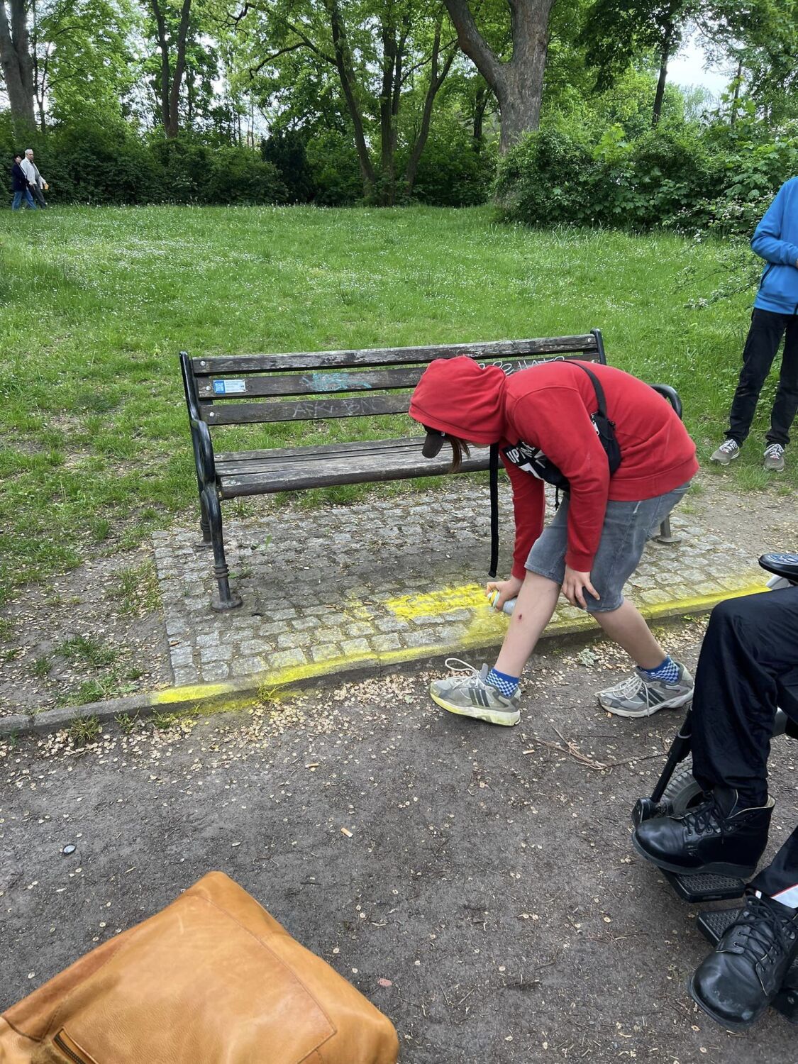 Vor der Bank ist die Kante zwischen Weg und Bodenplatte sehr hoch. Rollatornutzer*innen haben somit Schwierigkeiten, die Bank zu erreichen. Rollstuhlnutzer*innen müssen auf der Wiese stehen. Das ist vor allem nach Regen problematisch, weil der Boden matschig sein kann. Auch dort wurde auf diese Barriere mit Kreidespray aufmerksam gemacht.