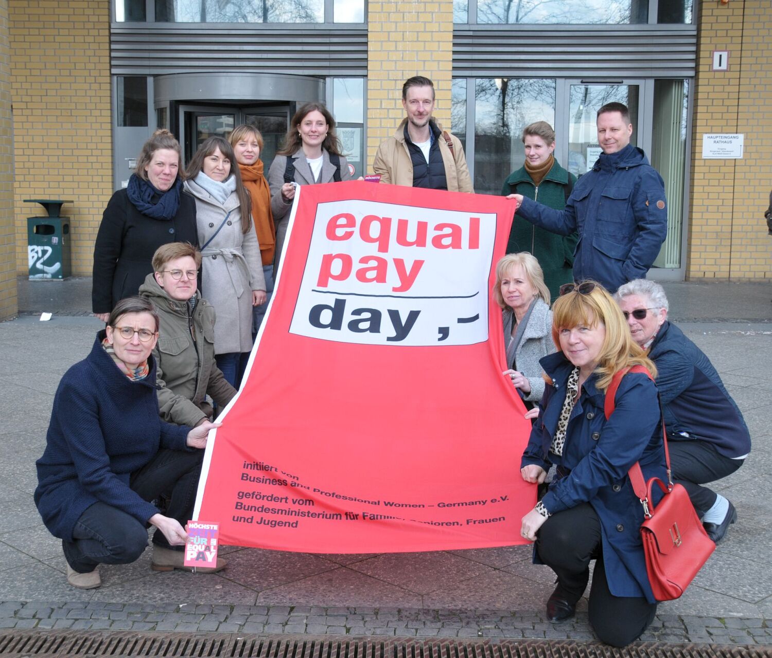 Fahnenhissung zum "Equal Pay Day 2024" - Juliane Witt, Heike Wessoly, Gordon Lemm, Stefan Bley und die Beauftragten Maja Loeffler und Vanessa Krah halten die Fahne