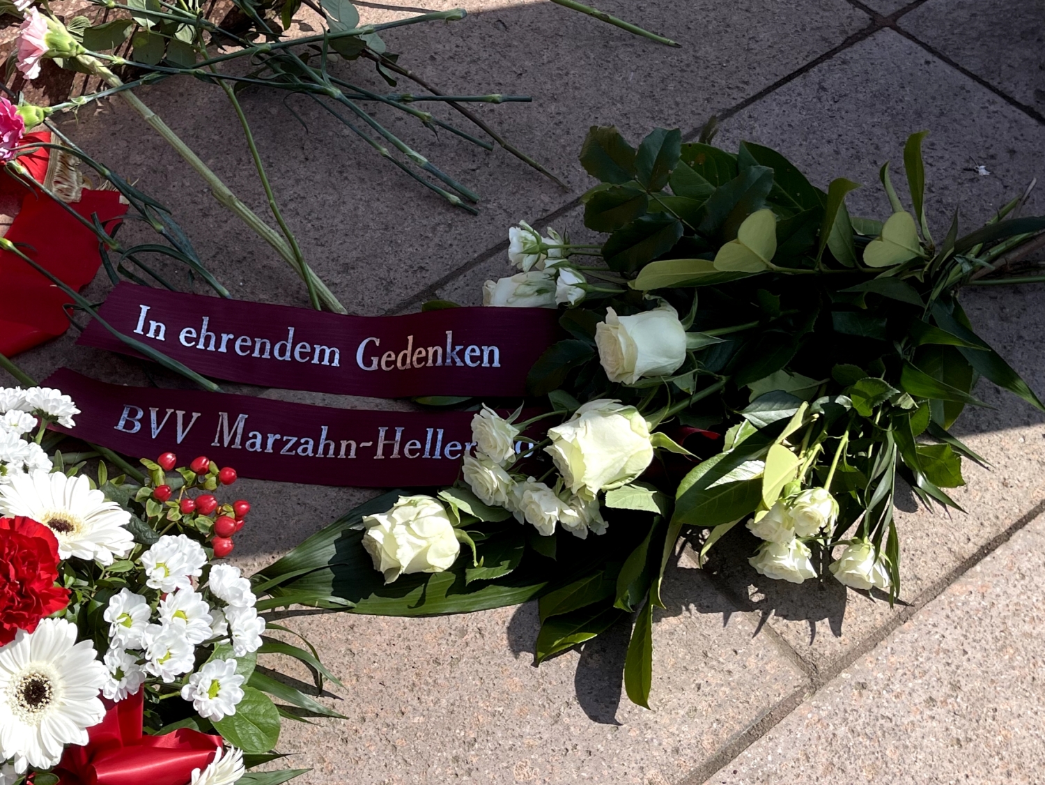 Blumengebinde weiße Rosen und Schleife mit der Aufschrift In ehrendem Gedenken BVV Marzahn-Hellersdorf