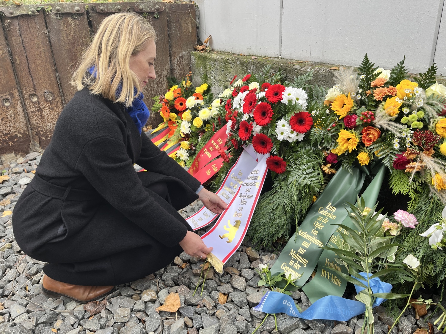 Bezirksstadträtin Dr. Almut Neumann richtet die Kranzschleife bei der Gedenkfeier zur Erinnerung an die Reichspogromnacht am Gedenkort Güterbahnhof Moabit.