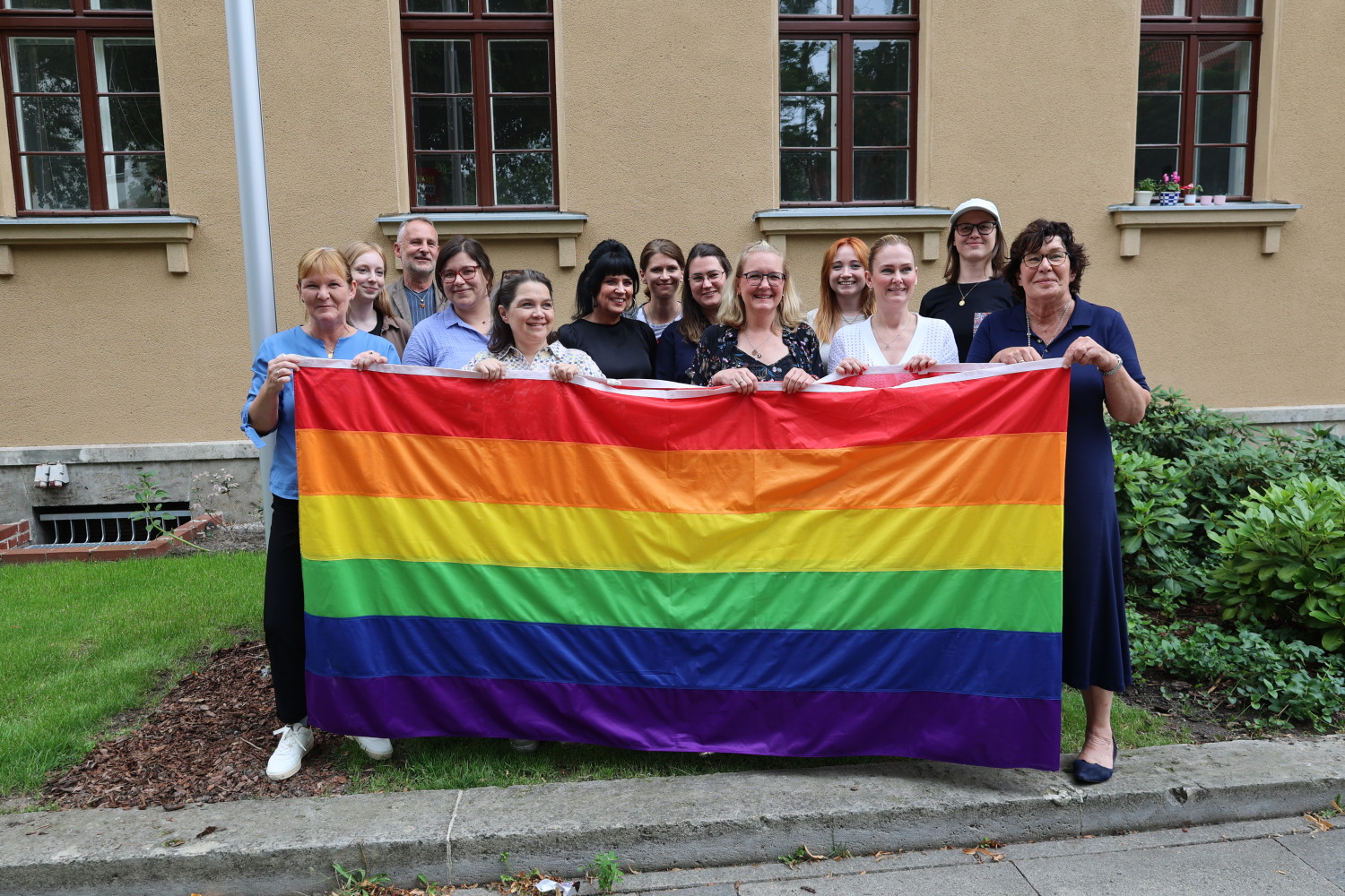 Beschäftigte des Bezirksamtes Steglitz-Zehlendorf gemeinsam mit Bezirksstadträtin Carolina Böhm (vorne links) und Bezirksbürgermeisterin Maren Schellenberg (vorne rechts) mit einer Regenbogenflagge