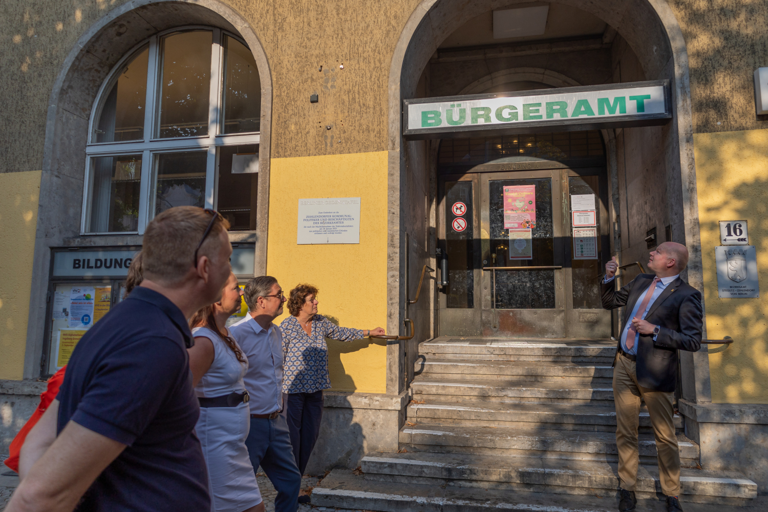 Bezirksstadtrat Tim Richter zeigt bei der Eröffnung des neuen Ausbildungsbürgeramts in Zehlendorf auf das Schild "Bürgeramt"