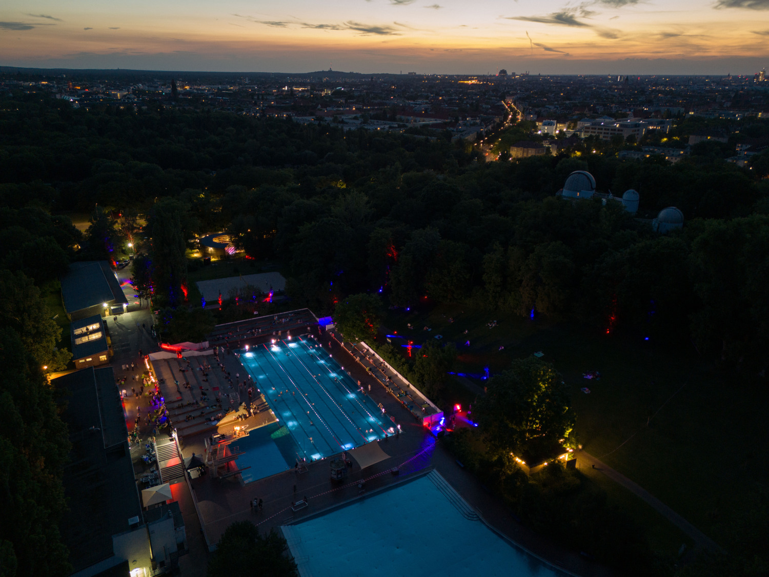 Drohnenaufnahme vom beleuchteten Sommerbad am Insulaner bei Abenddämmerung