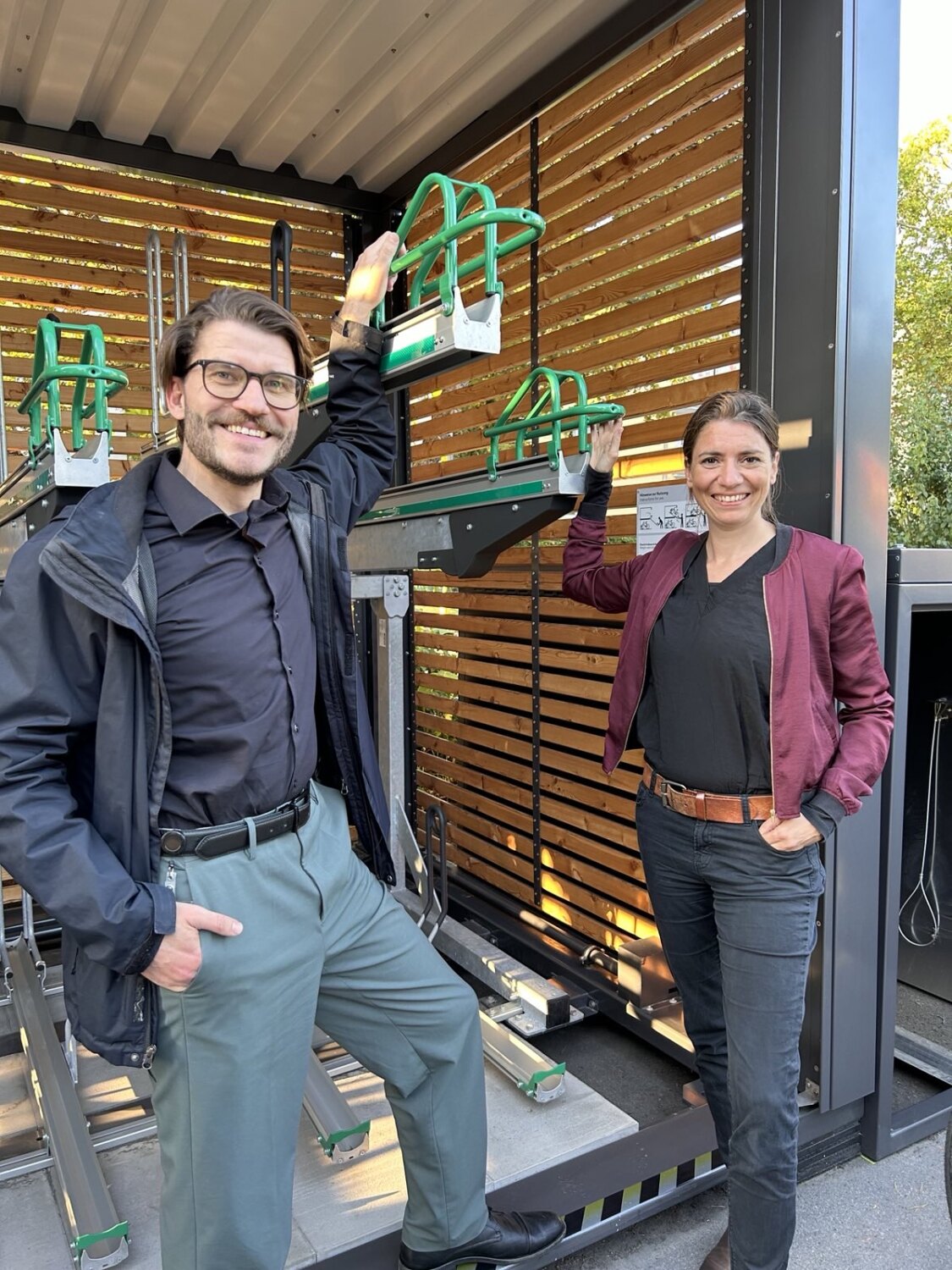 Eine Frau und ein Mann stehen vor einem Container, in dem Fahrräder abgestellt werden können.