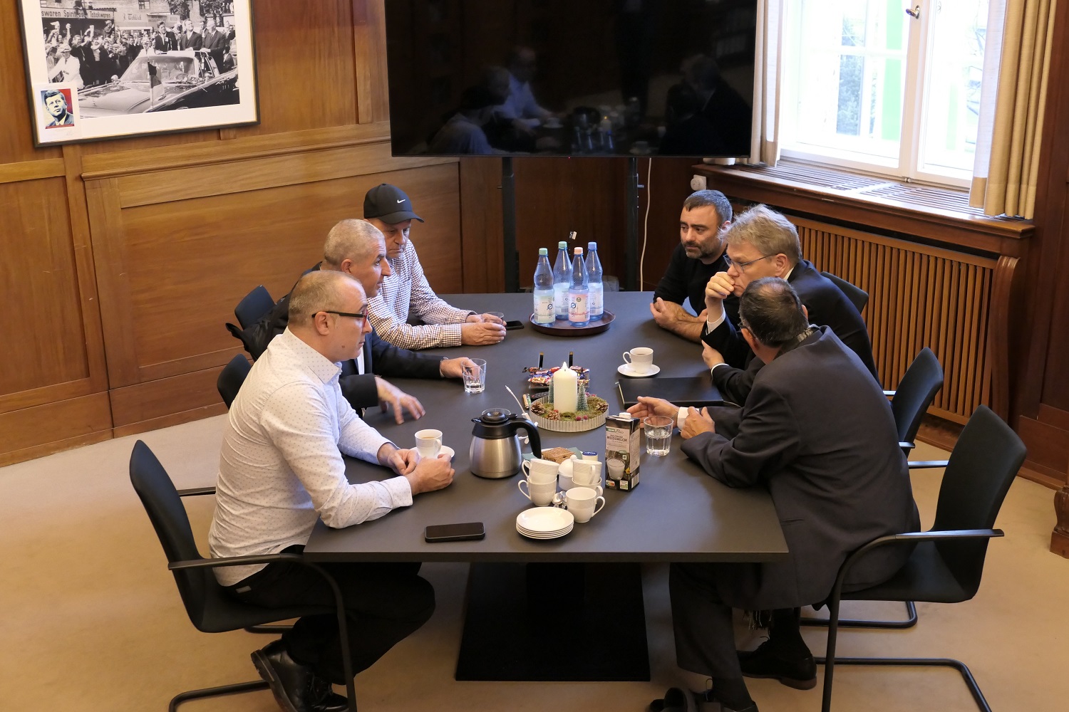 sechs Menschen sitzen an einem Tisch und besprechen sich