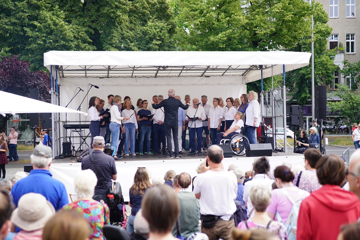 viele singende Menschen auf einer Open-Air-Bühne