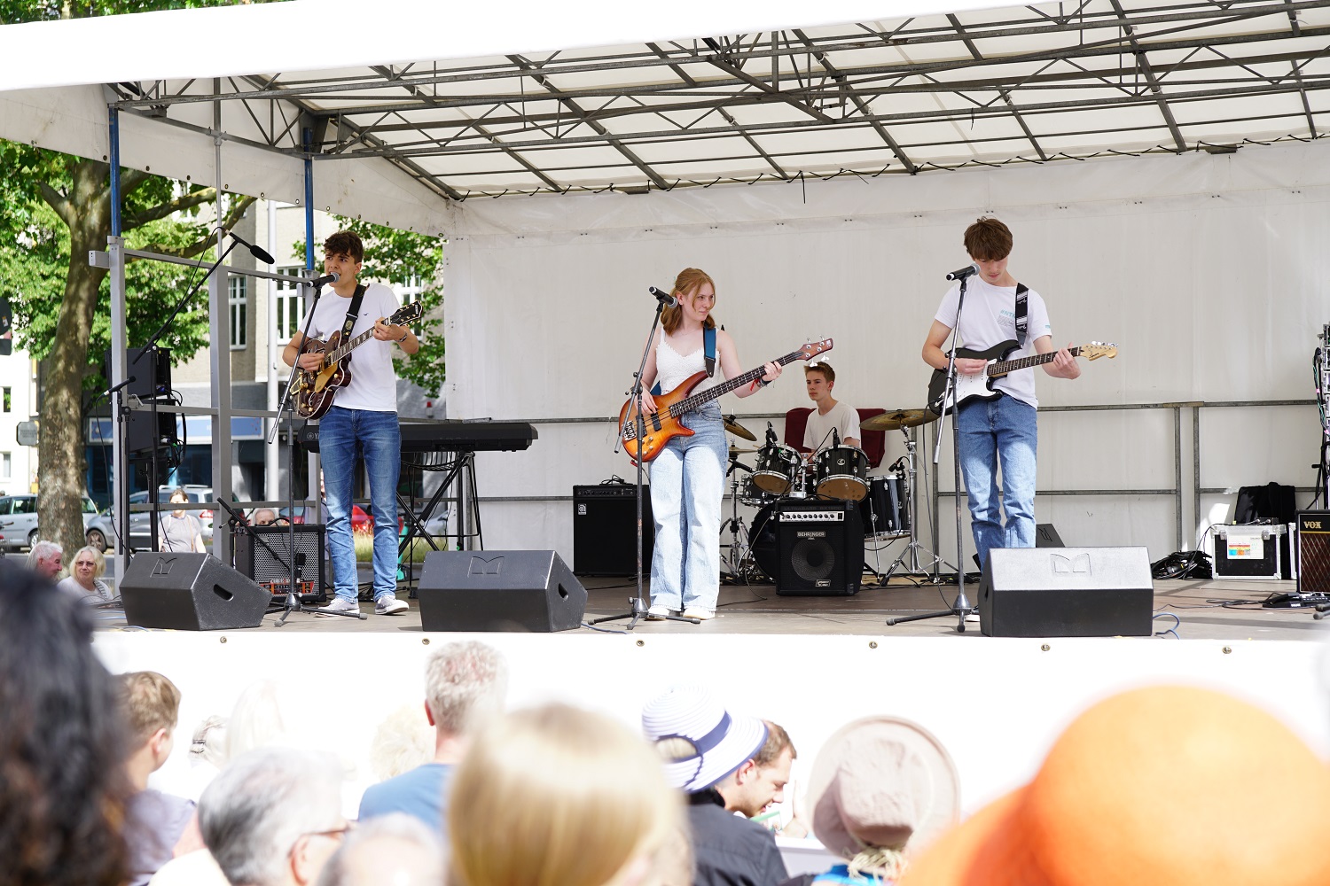 vier junge Menschen, die auf einer Open-Air-Bühne musizieren