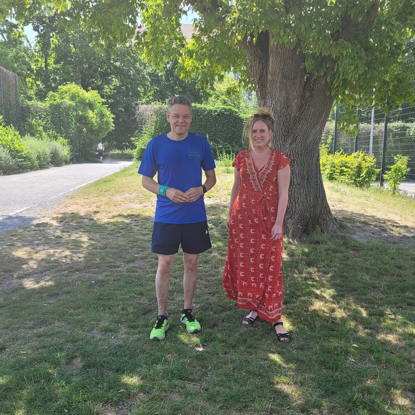 Eine Frau und ein Mann stehen auf einer Wiese unter einem Baum 