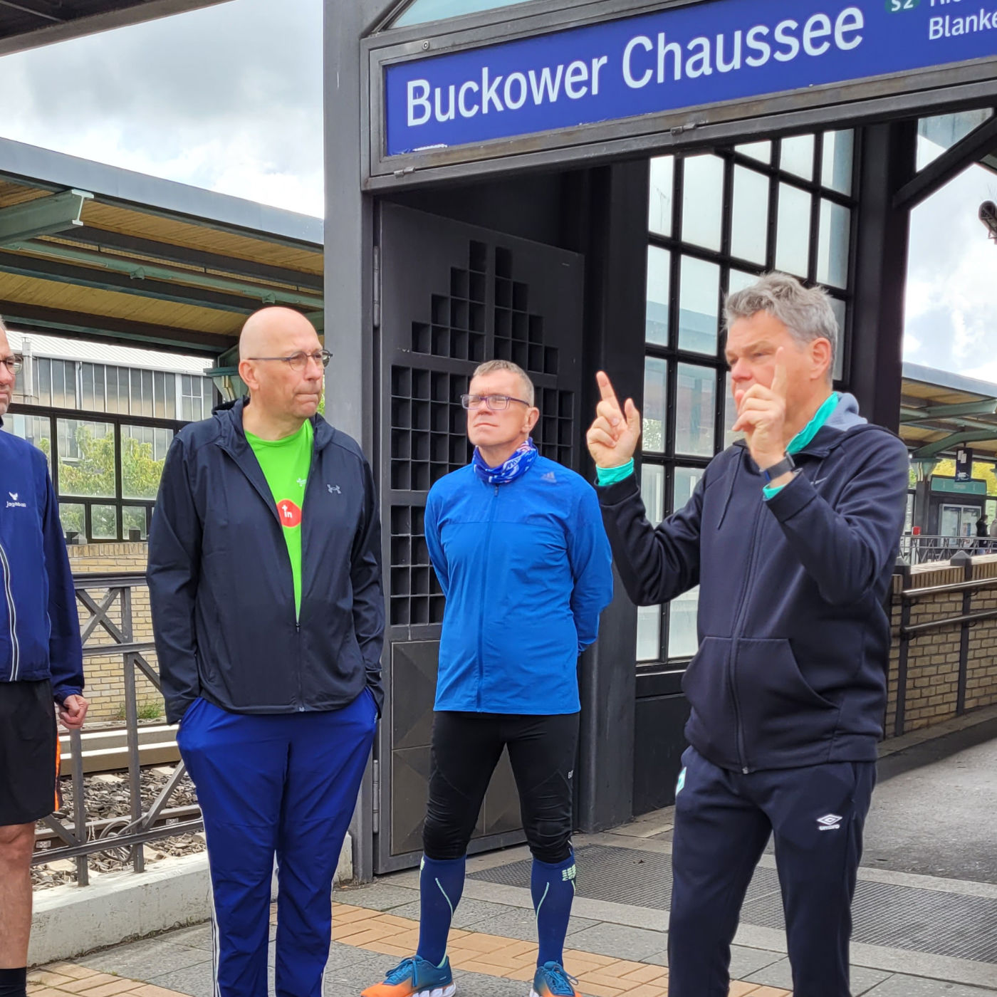 Drei Läufer stehen vor einem Bahnhof