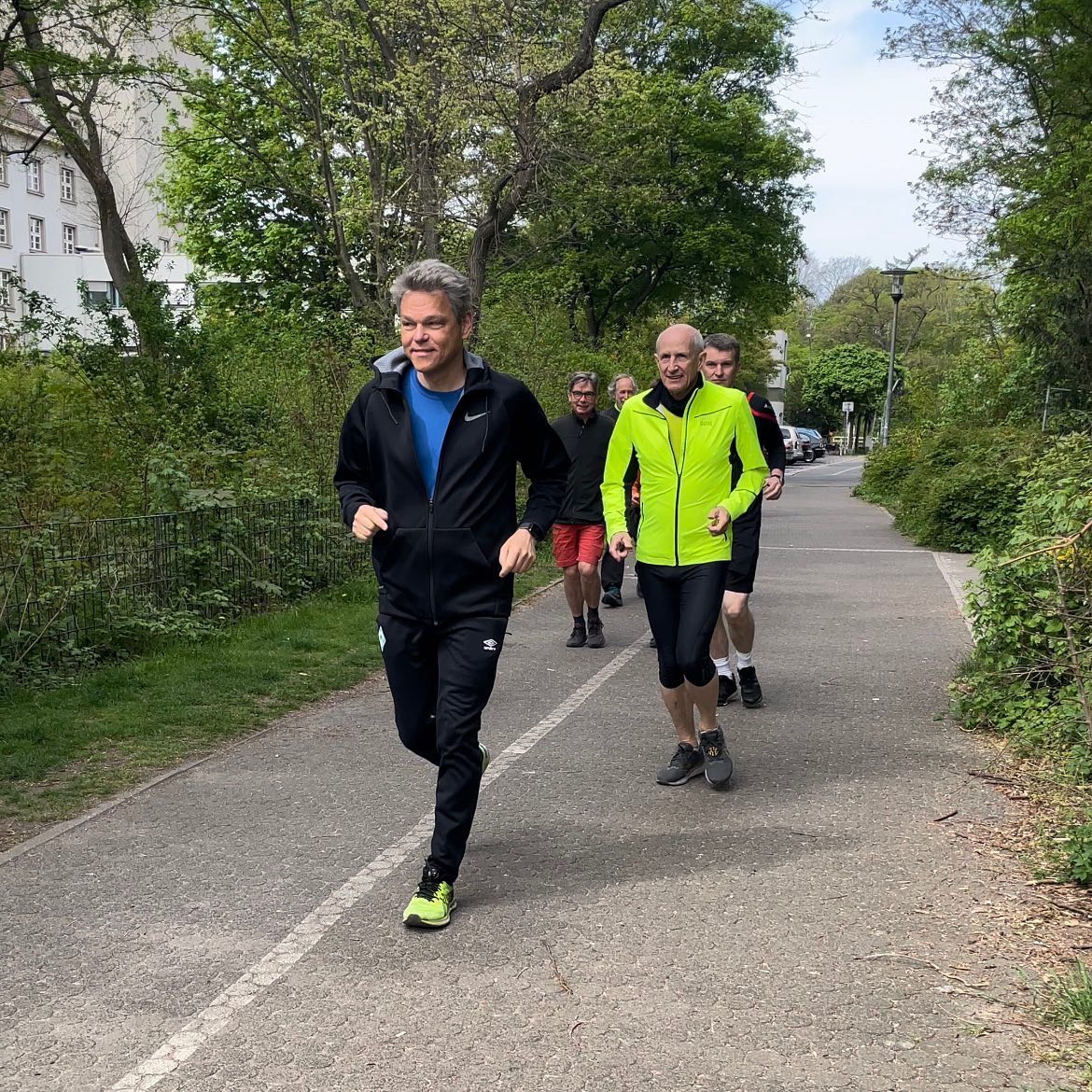 mehrere Personen joggen durch einen Park