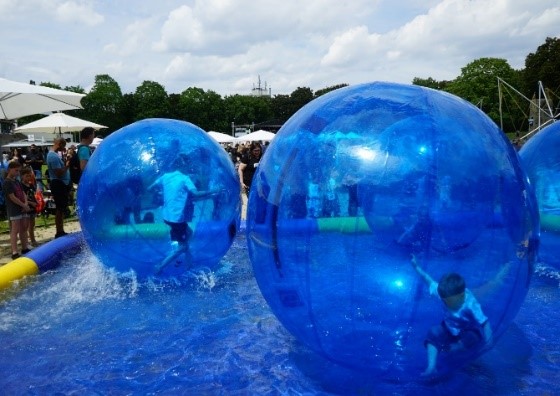 Pool mit Wasserlaufbällen, in denen Kinder über das Wasser laufen