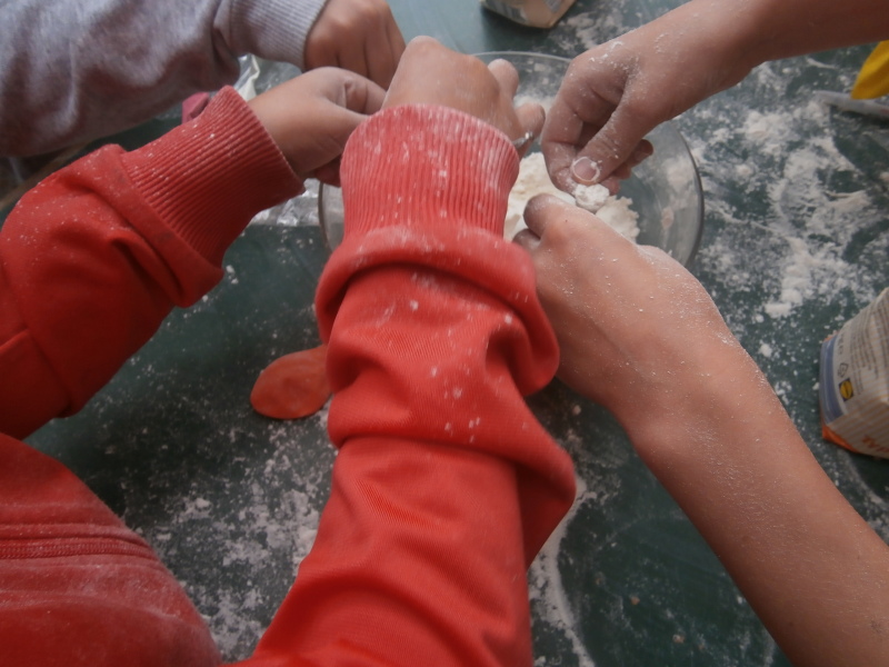 Kinderhände arbeiten mit Mehl.