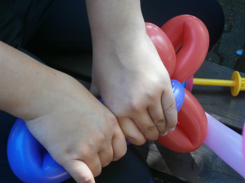 Luftballon wird mit Händen geformt.