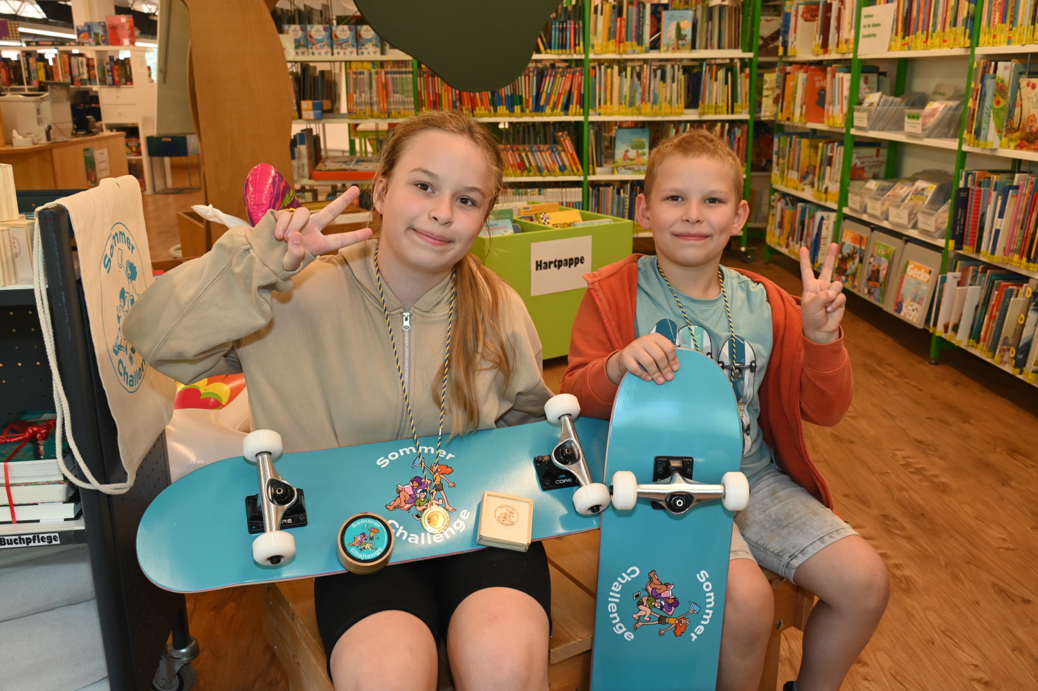 zwei Kinder mit Skateboard in der Bibliothek