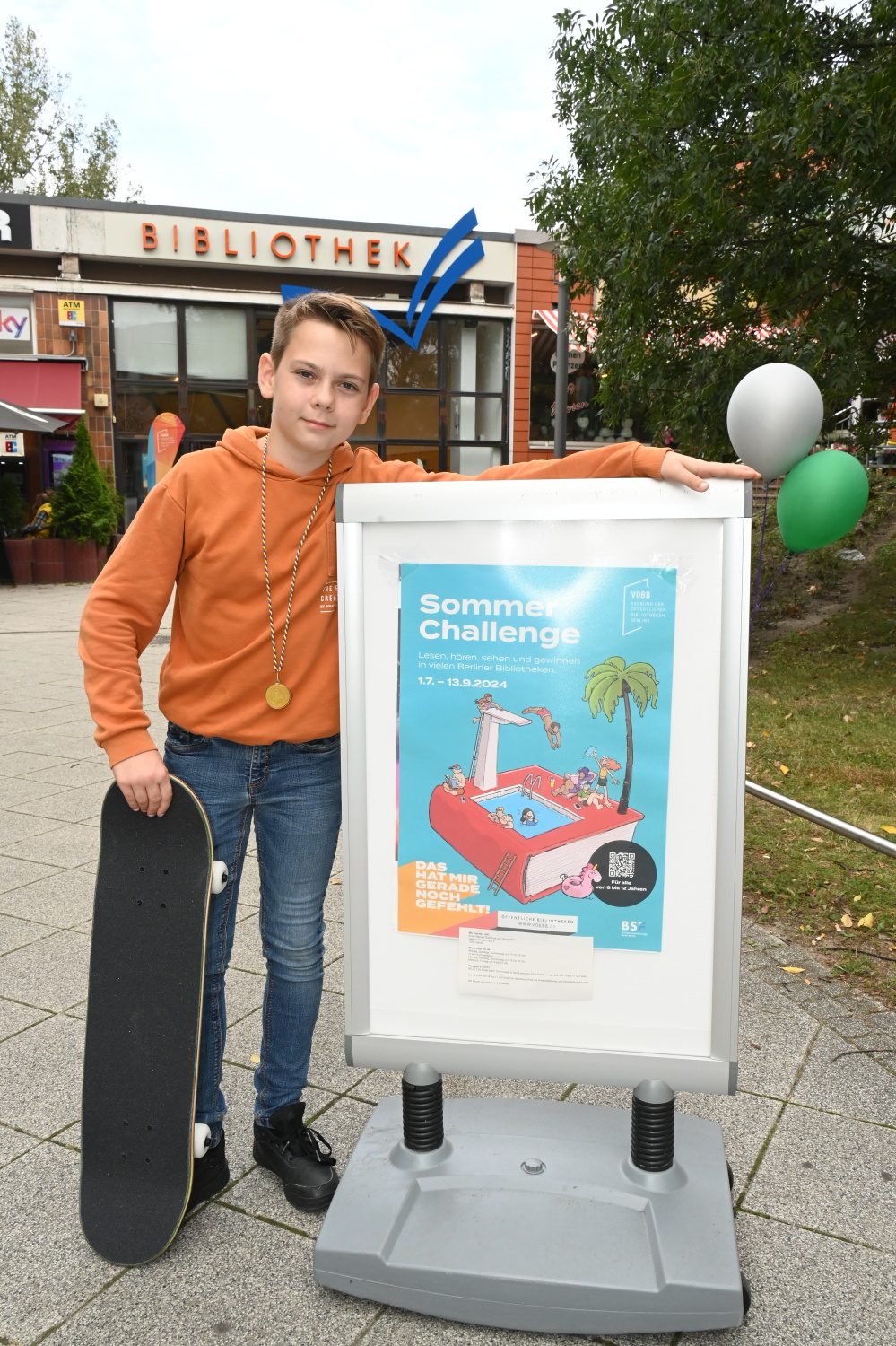 ein Junge mit Skateboard vor der Bibliothek