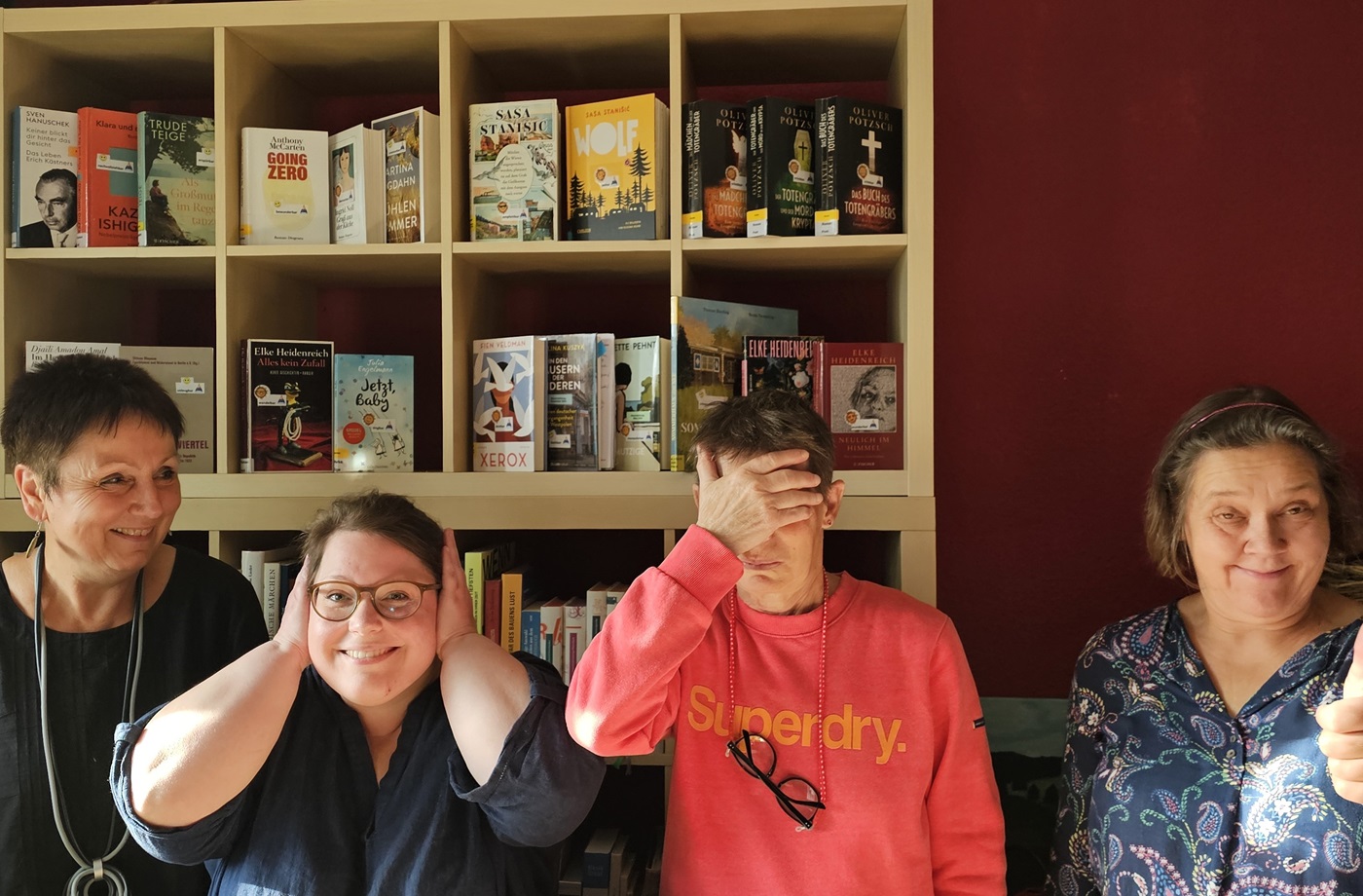 vier Frauen stehen lachend vor einem Bücherregal