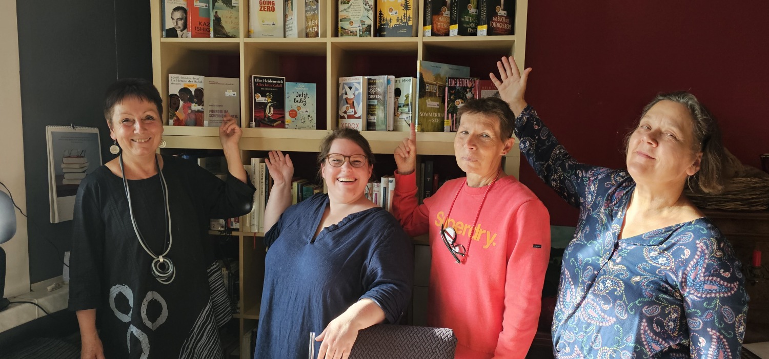 vier Frauen stehen vor einem Bücherregal