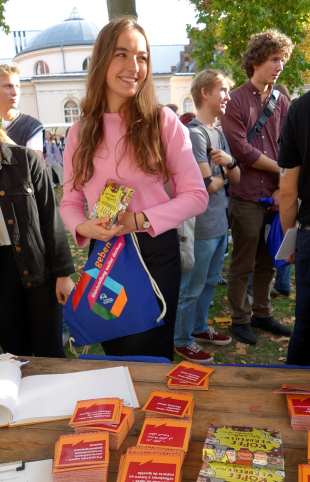 Studentin hält mehrere Giveaways in den Händen und lächelt.